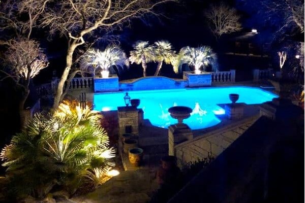 A beautifully lit pool with bubblers inside and plants all around