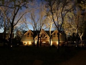 a cabin in the wood lit up with exterior lighting