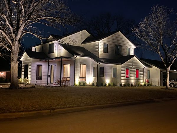 white wooden home lit up with landscape lighting