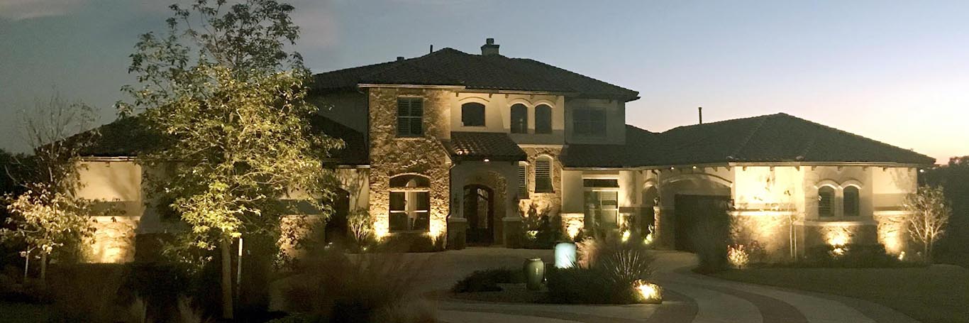 stone home and landscape lit up with outdoor lighting
