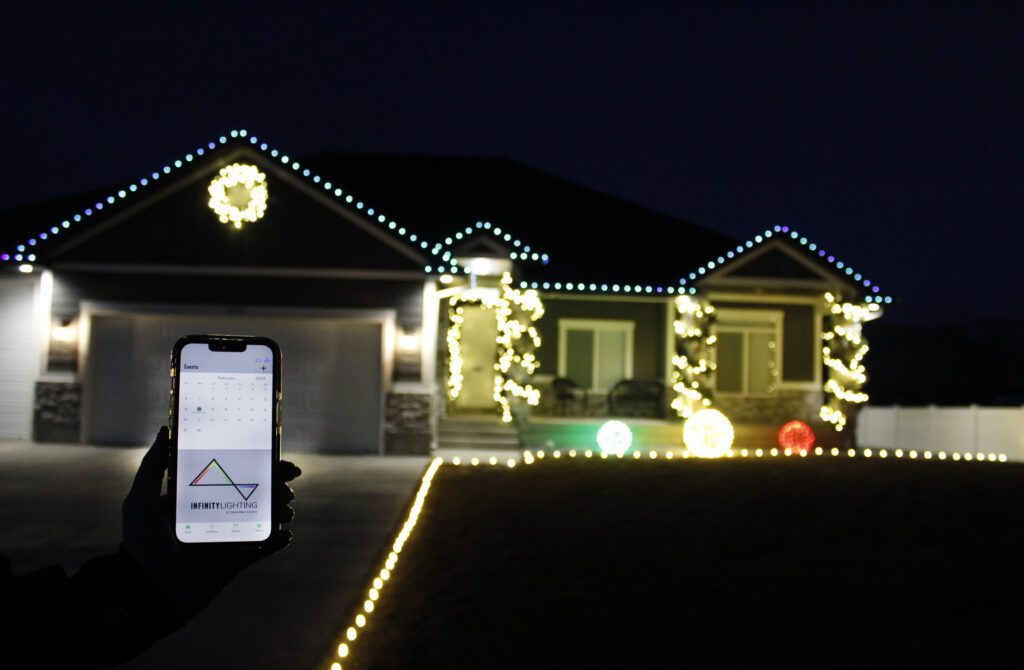 A street view of a house with Christmas lights being controlled by an app on a phone.