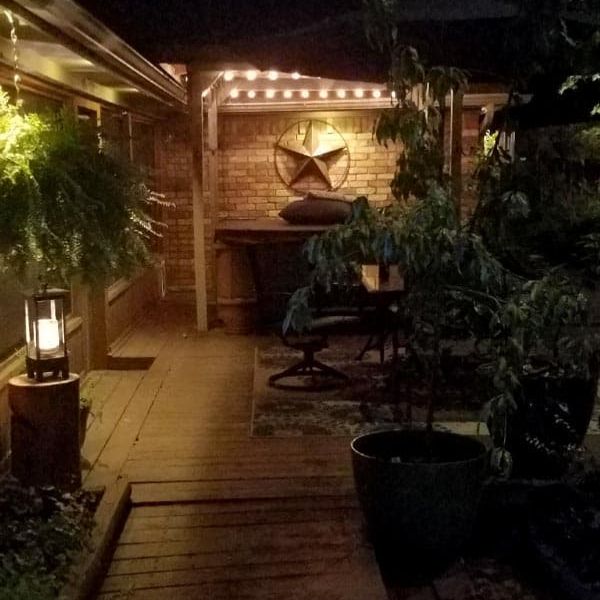 Outdoor deck at night featuring hanging fern, cozy seating area, and warm lighting